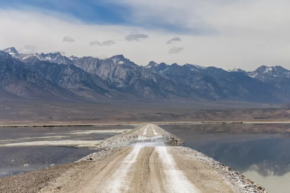 Unpaved road through Owens Lake bed with Sierra Nevada mountains in the background